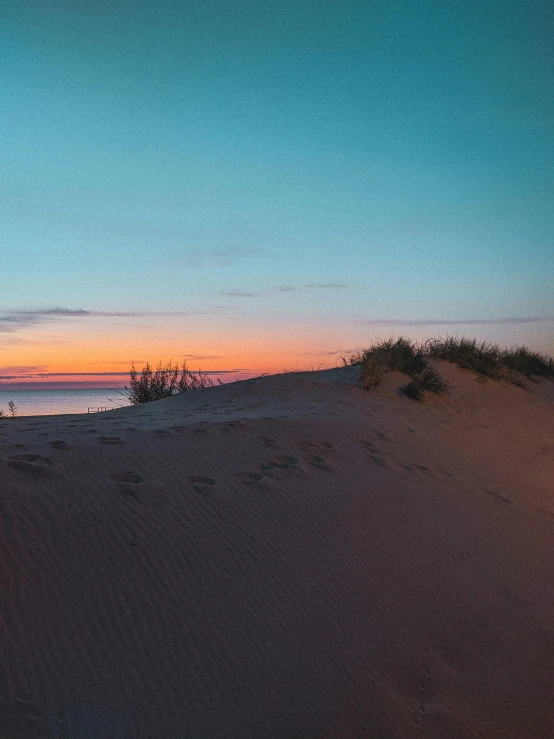 a beach at sunset with footprints in the sand, unsplash contest winner, land art, dune (2021), ukraine. photography, dusk sky, today\'s featured photograph 4k