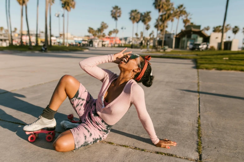 a woman sitting on the ground on a skateboard, trending on pexels, pink clothes, having fun in the sun, ( ( dark skin ) ), recovering from pain