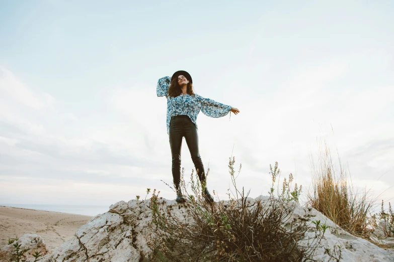 a woman standing on top of a pile of dirt, trending on pexels, hippie fashion, blue, positing on rock super hero pose, wearing casual clothing