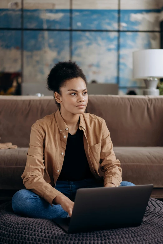 a woman sitting on the floor using a laptop, trending on pexels, renaissance, mixed-race woman, sitting on couch, official screenshot, looking across the shoulder