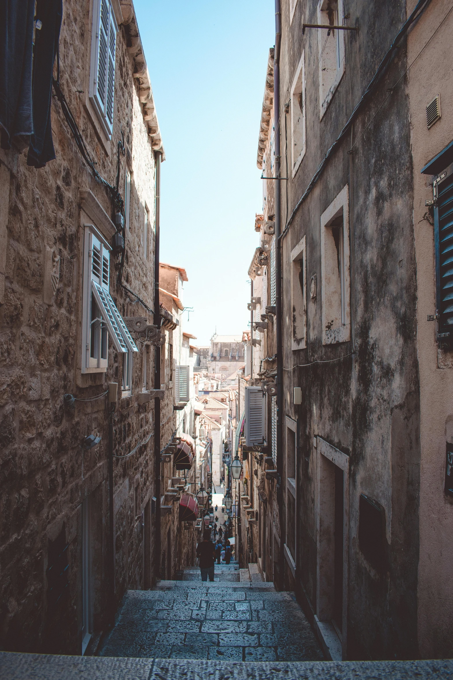 a narrow street with people walking down it, a picture, croatian coastline, vintage aesthetic, lots of building, cities