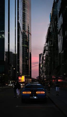 a car driving down a street next to tall buildings, an album cover, pexels contest winner, sunset evening lighting, melbourne, neon backlit, cars and people