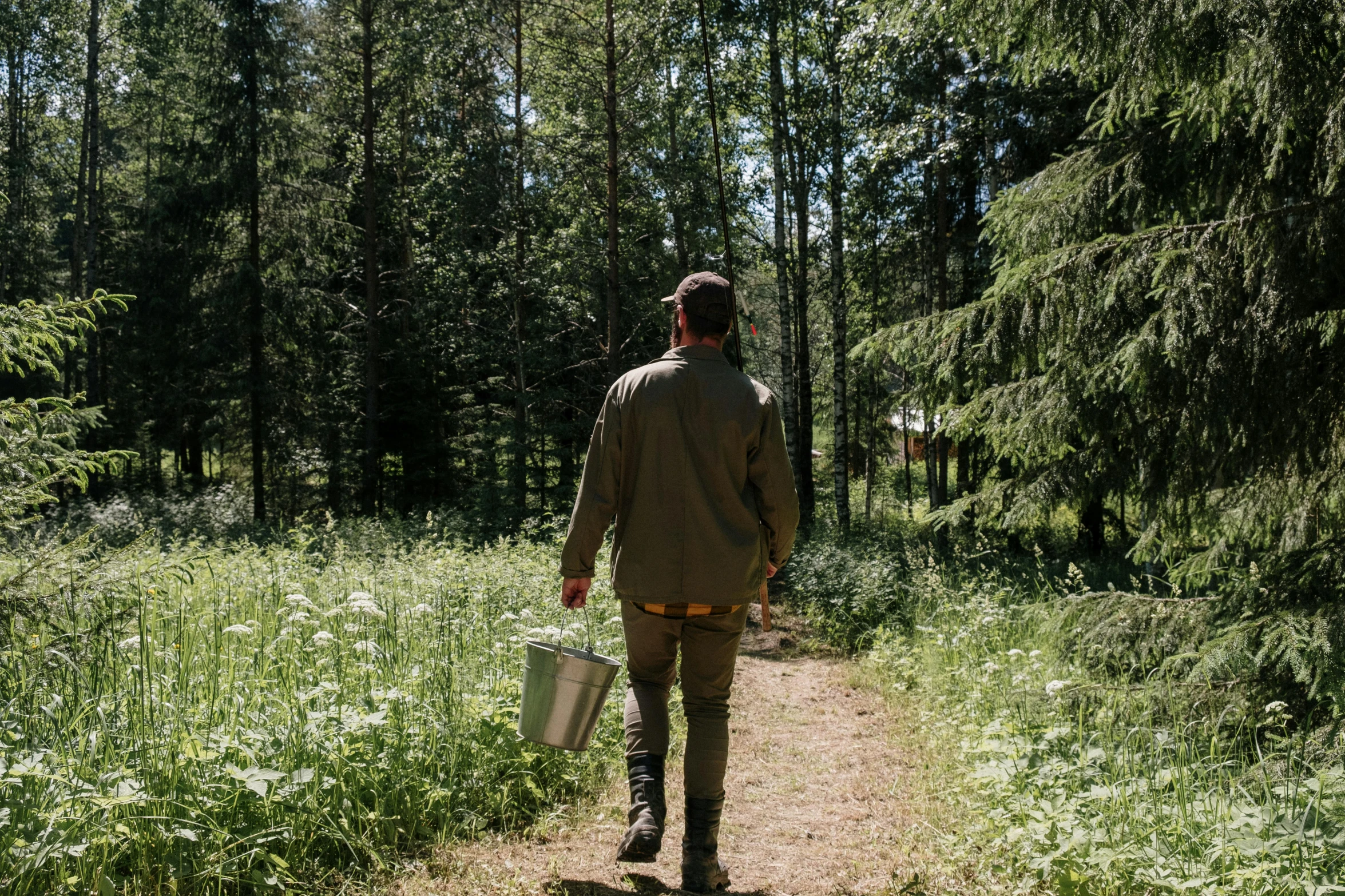 a man walking down a dirt path in the woods, inspired by Eero Järnefelt, unsplash, wearing farm clothes, midsummer, ready to eat, fishing