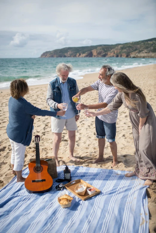 a group of people standing on top of a beach, wine, linen, near the beach, musician