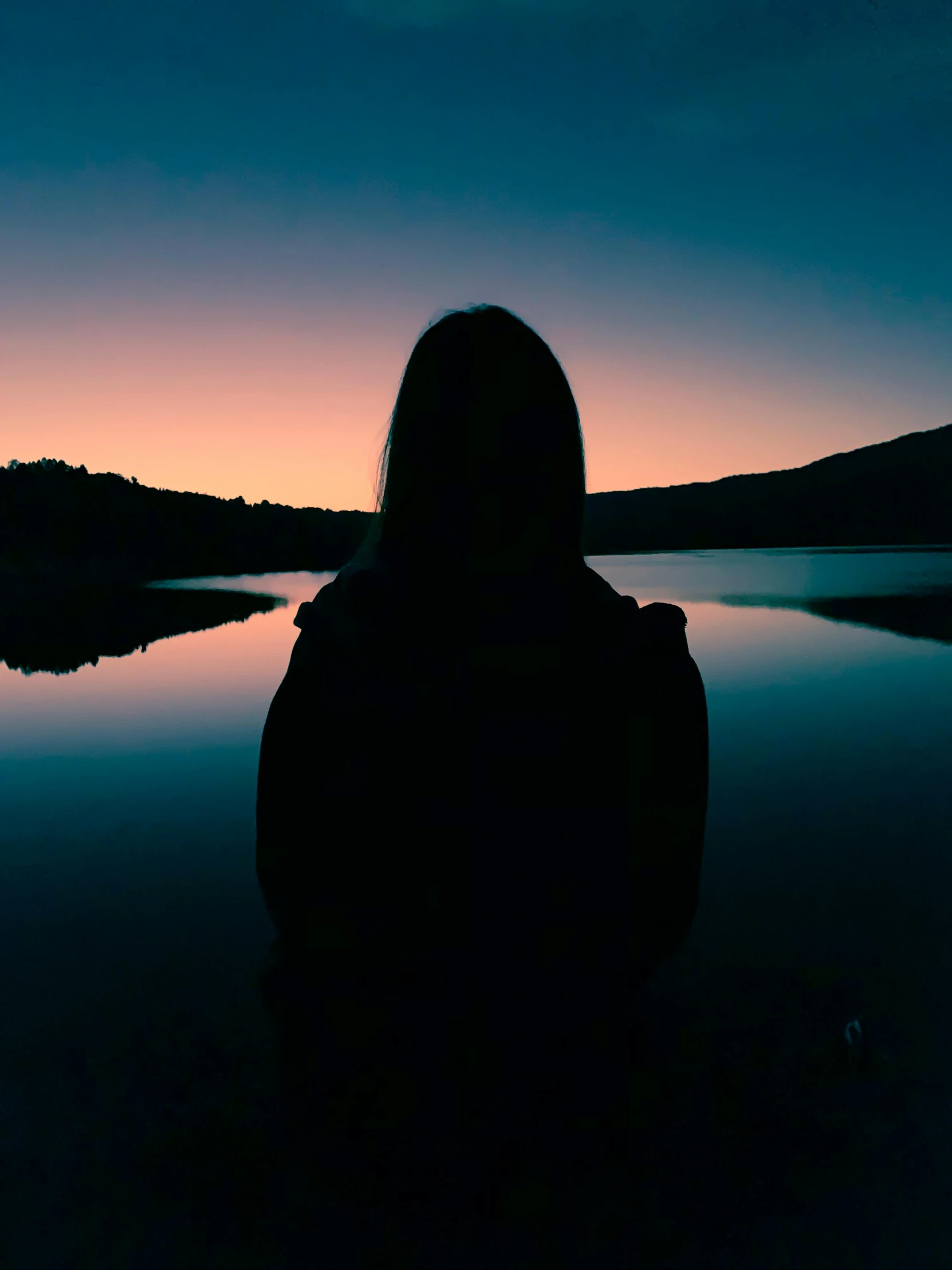 a person standing in front of a body of water, out in the dark, sitting in front of a lake, outlined silhouettes, back facing the camera