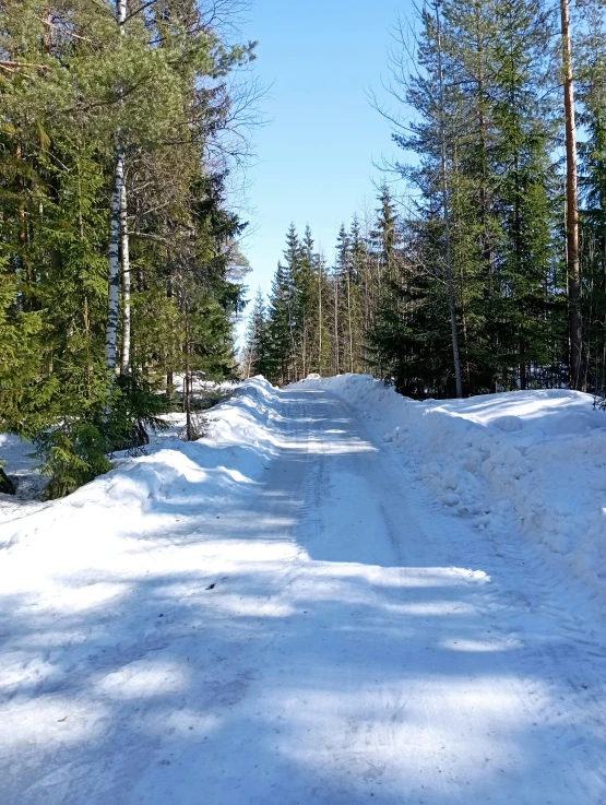 a man riding a snowboard down a snow covered slope, by Veikko Törmänen, hurufiyya, road in a forest road, driveway, empty road in the middle, photograph taken in 2 0 2 0