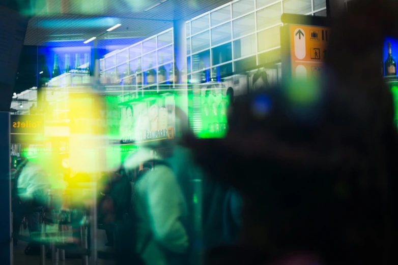 a blurry photo of people walking through a store, pexels contest winner, happening, blue and green light, black. airports, cyberpunk pincushion lens effect, translucent neon