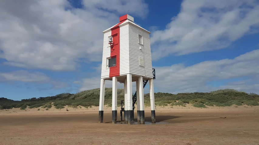 a white and red tower sitting on top of a sandy beach, inspired by Storm Thorgerson, unsplash, photorealism, david bates, square, carrington, photograph taken in 2 0 2 0