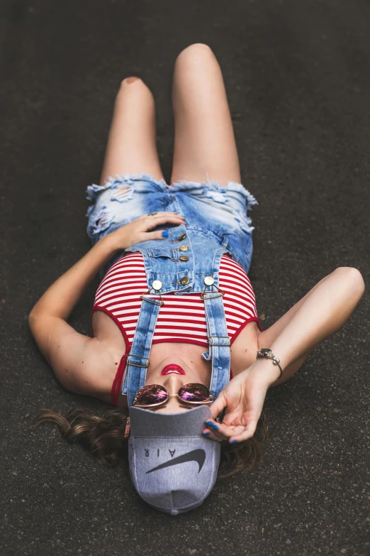 a woman laying on the ground using a cell phone, pexels contest winner, overalls, doing a sassy pose, red and white stripes, bra and shorts streetwear