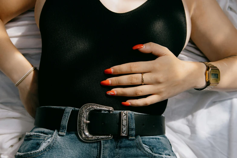 a woman laying on a bed with her hands on her stomach, inspired by Elsa Bleda, trending on pexels, aestheticism, nail polish, wide belt, red on black, long nails