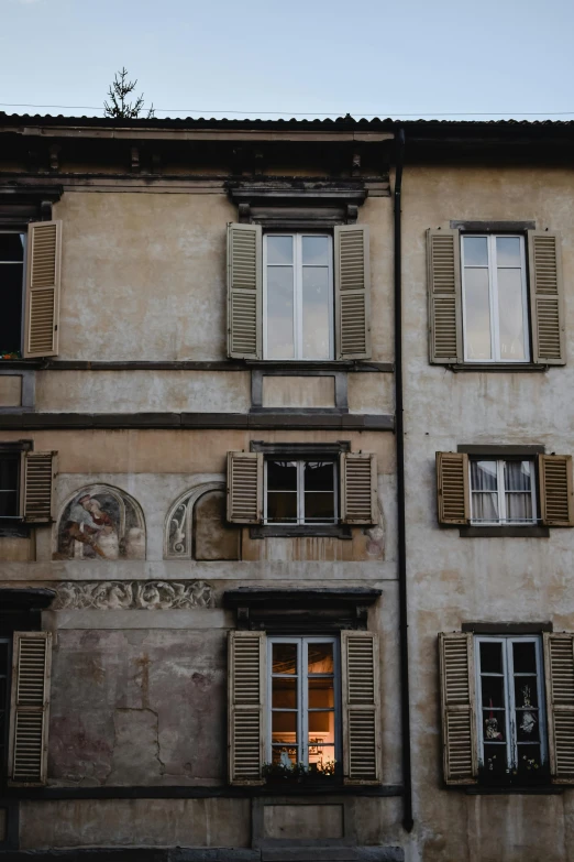 a tall building with lots of windows and shutters, inspired by Eliseu Visconti, pexels contest winner, renaissance, light - brown wall, faded worn, window ( city ), carvaggio