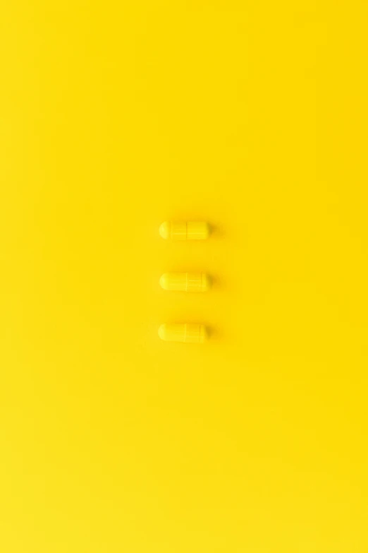 a couple of screws sitting on top of a yellow surface, inspired by Andreas Gursky, unsplash, minimalism, pills, ffffound, 3 - piece, resin