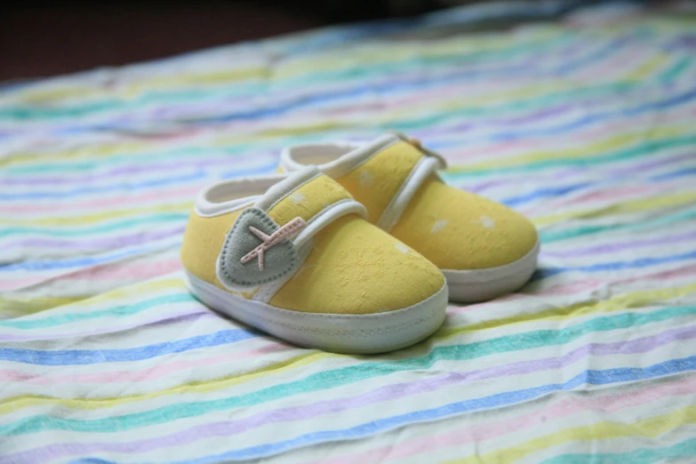 a pair of yellow shoes sitting on top of a bed, toddler, slight yellow hue, pochi iida, scrapbook