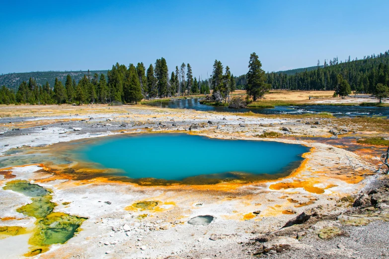 a blue pool of water surrounded by trees, a colorized photo, by Julia Pishtar, trending on unsplash, wyoming, sulfur, craters, meadows