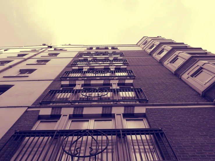 a tall building with a clock on the side of it, a photo, inspired by Albert Paris Gütersloh, unsplash, paris school, balconies, bleak tone, view from ground level, 90s photo