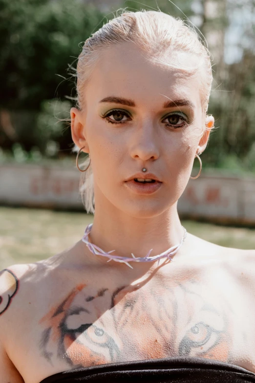 a woman with a tattoo on her chest, inspired by Elsa Bleda, antipodeans, pastel pink skin tone, pearl choker, solar punk product photo, looking towards camera
