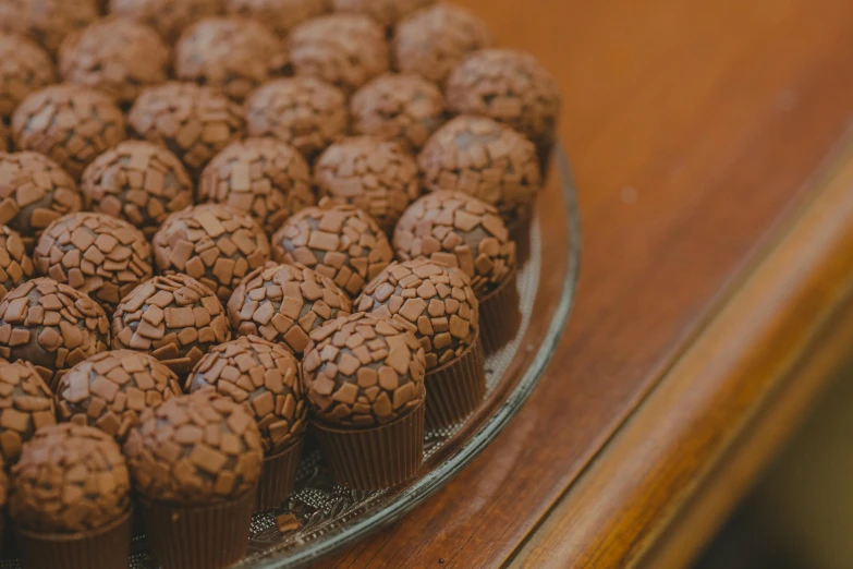 a plate of chocolate cupcakes sitting on a table, by Elsa Bleda, pexels contest winner, dragon eggs, thumbnail, brazilian, incredibly detailed