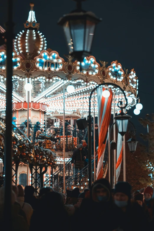 a group of people standing around a carousel at night