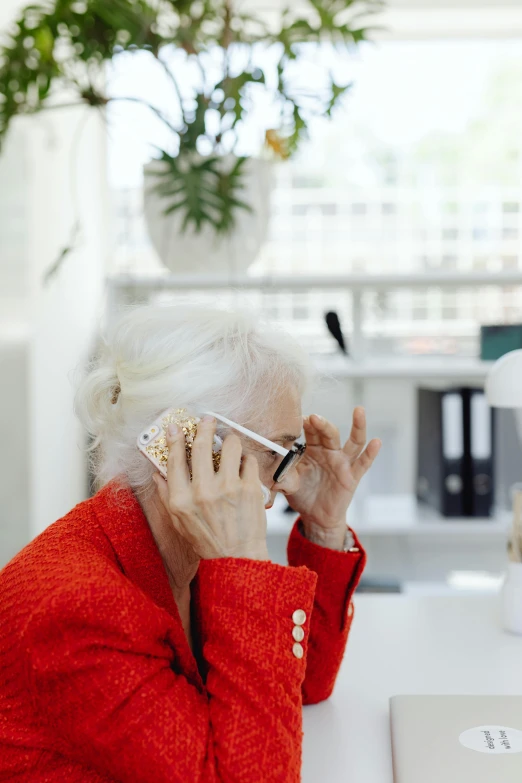 a woman sitting at a desk talking on a cell phone, by Jan Tengnagel, trending on pexels, blinding white hair, oled visor over eyes, fashionable, facepalm