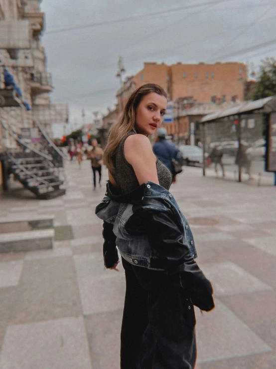 a woman standing in the middle of a street, leather jacket and denim vest, dasha taran, low quality photo, 🤬 🤮 💕 🎀