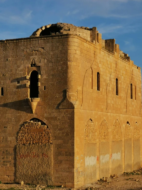 a large brick building sitting on top of a dirt field, by Muggur, romanesque, old town mardin, sun down, splash image