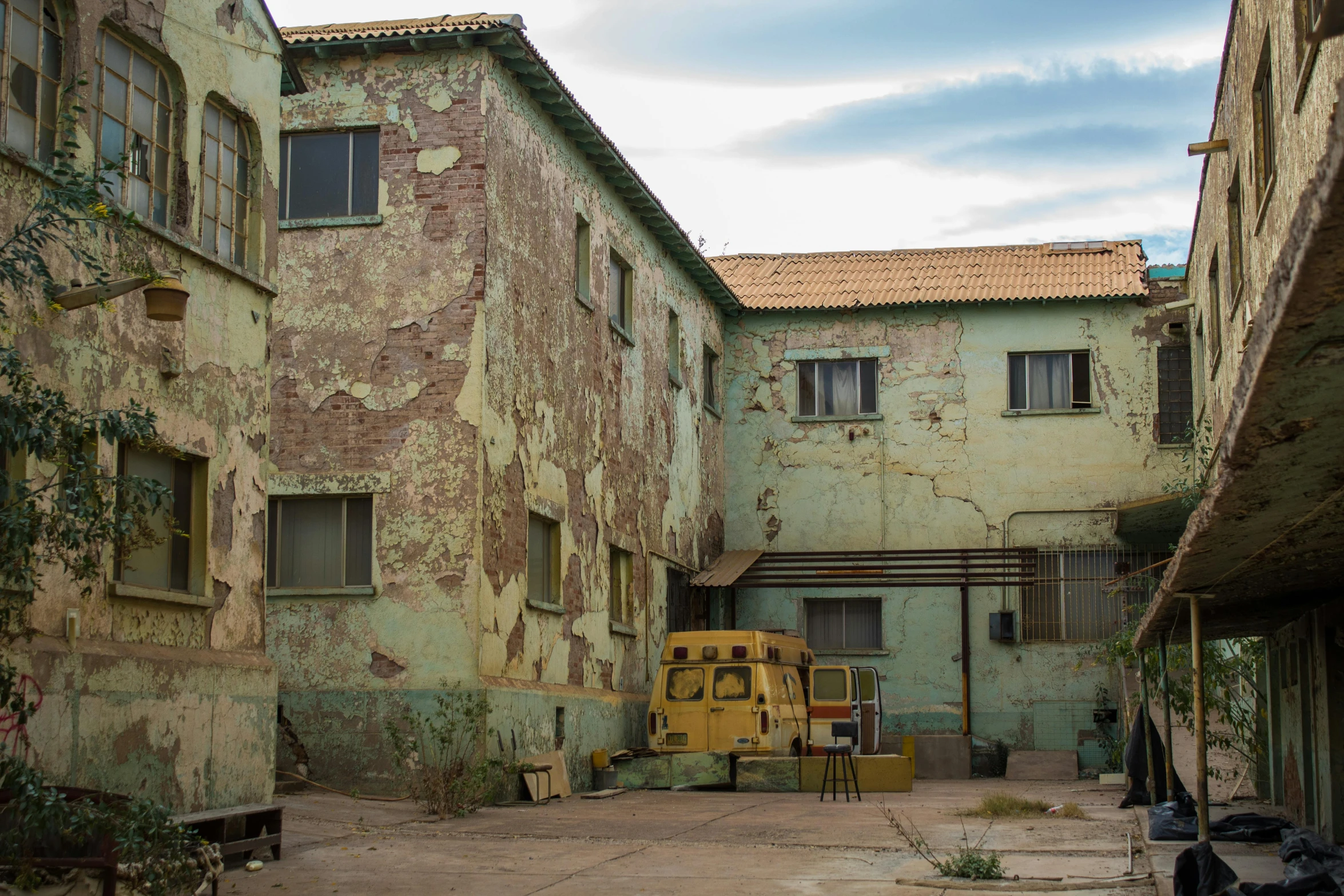 an old building with a yellow bus parked in front of it, a detailed matte painting, by Elsa Bleda, pexels contest winner, arte povera, an abandonded courtyard, brown, military buildings, ((rust))