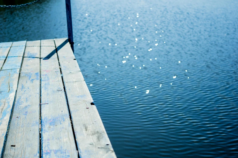 a wooden dock next to a body of water, a picture, by Elsa Bleda, unsplash, sparkling water, blue, surface imperfections, a wooden