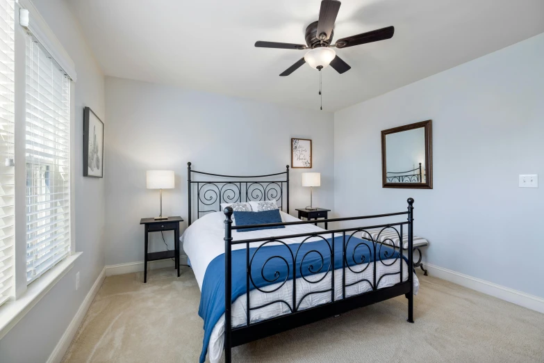 a bed room with a neatly made bed and a ceiling fan, by Carey Morris, unsplash, arabesque, blue accents, wrought iron, listing image, 120 degree view