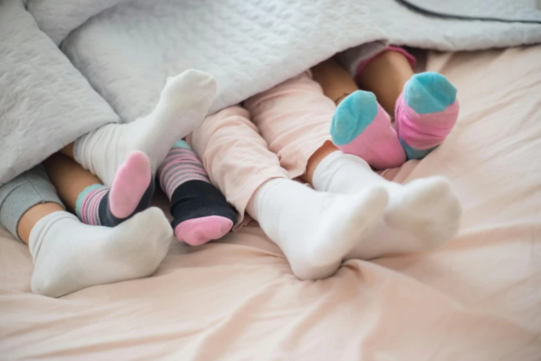 a couple of little girls laying on top of a bed, inspired by Sarah Lucas, pexels contest winner, incoherents, socks, pink white turquoise, concert, multicolored
