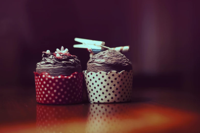 a couple of cupcakes sitting on top of a table, pexels, photorealism, polka dot, dark and intricate, brown, fan favorite