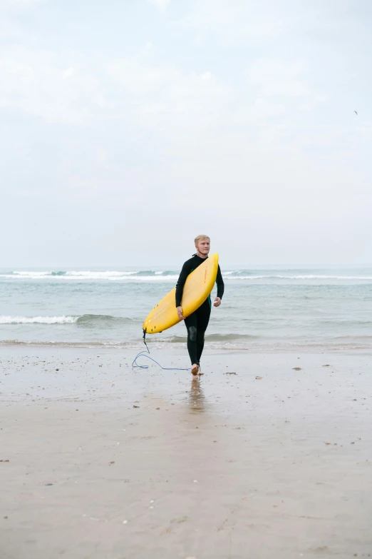 a man walking on a beach with a surfboard, black and yellow, bjørn, standing next to water, plain background