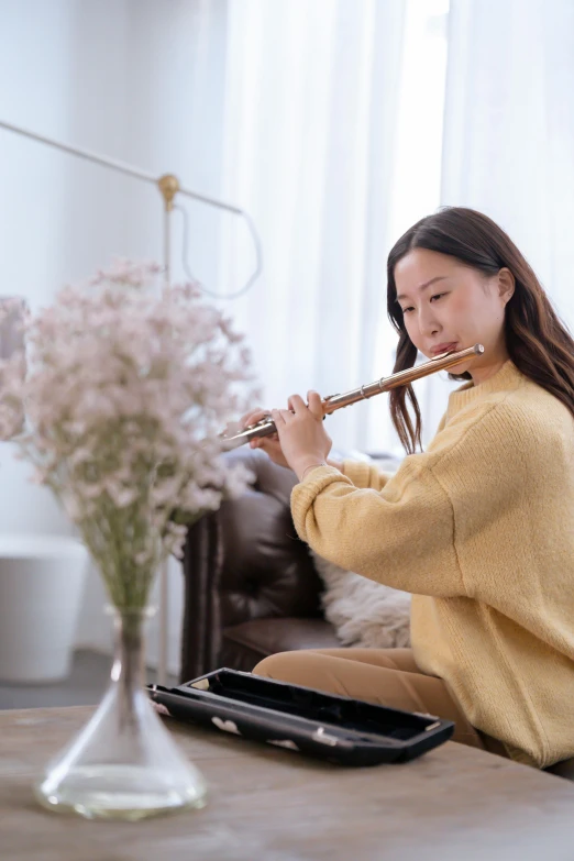 a woman sitting on the floor playing a flute, trending on pexels, sitting on a couch, blooming, qi sheng luo, promotional image