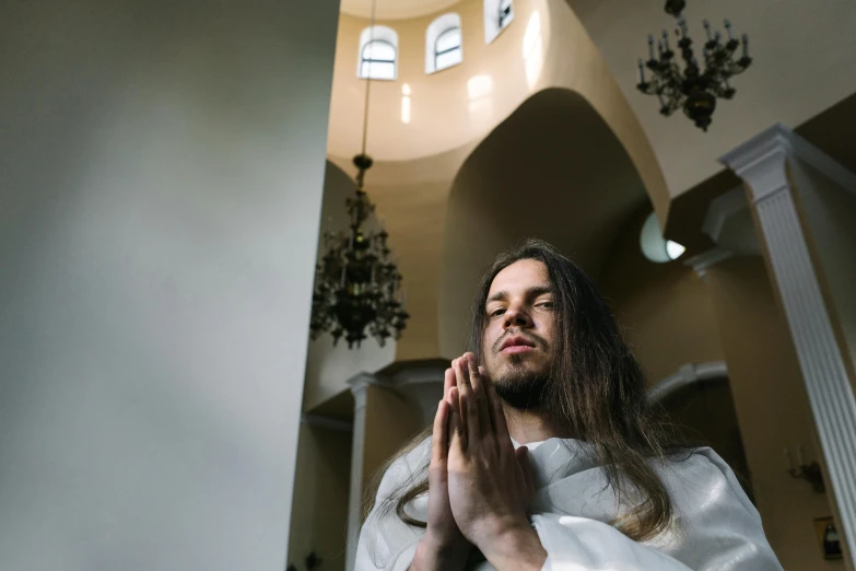 a man in a white robe is praying, an album cover, by Julia Pishtar, pexels contest winner, russian temple, orelsan, catholicpunk, extremely long hair