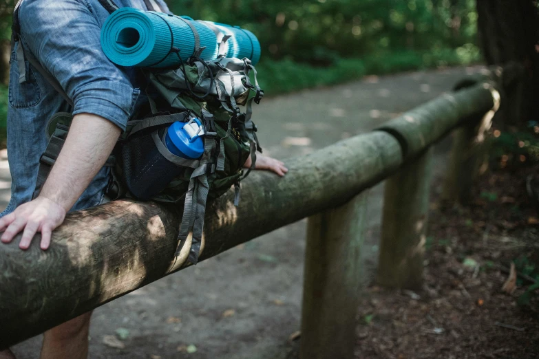 a man with a backpack sitting on a log, pexels contest winner, a cannon mounted on his back, ligjt trail, thumbnail, background image