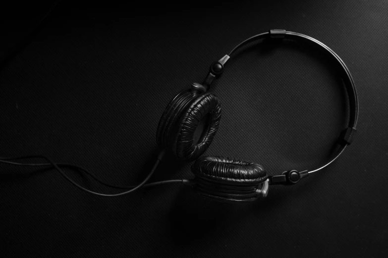 a pair of headphones sitting on top of a table, by Adam Marczyński, hurufiyya, black textured, high quality image, a pair of ribbed, dj