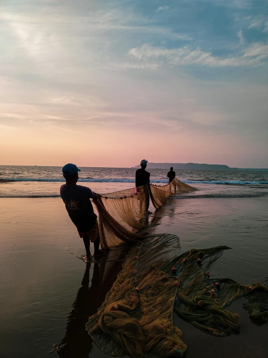 a group of men standing on top of a beach next to the ocean, nets, in the evening, profile image, fishing