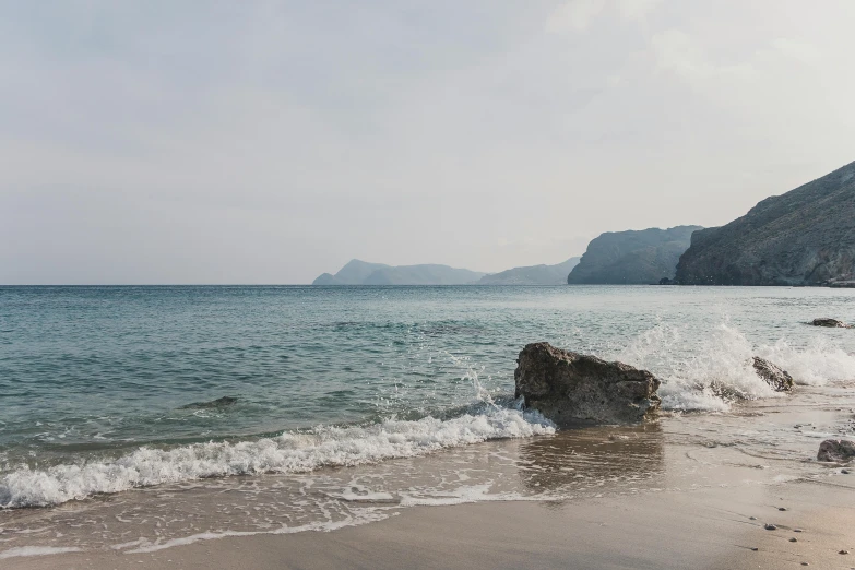 a man standing on top of a sandy beach next to the ocean, inspired by Exekias, pexels contest winner, minimalism, capri coast, view of sea, fiona staples, scylla and charybdis