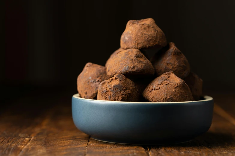 a bowl filled with chocolate truffles on top of a wooden table, unsplash, renaissance, background image, fuji choco, 1 6 x 1 6, potato