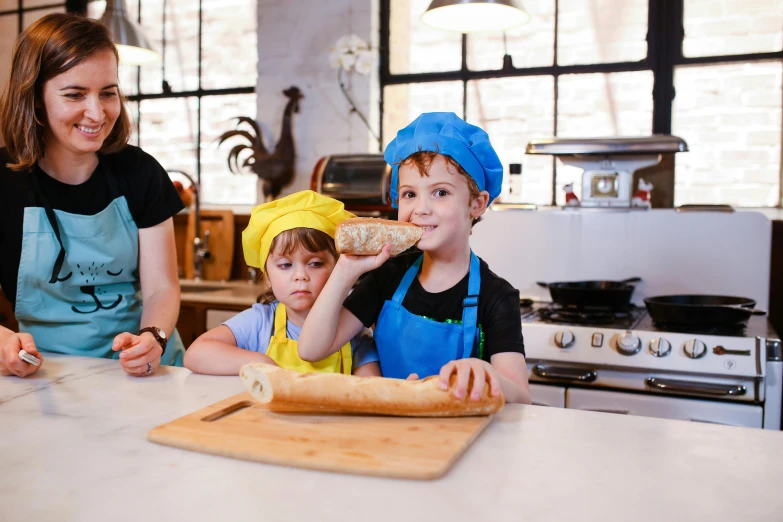 a woman and two children preparing food in a kitchen, pexels contest winner, holding a baguette, chef hat, lachlan bailey, cute boys