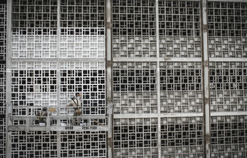 a black and white photo of a man in a cage, by Yasushi Sugiyama, brutalism, decorative panels, under repairs, wenfei ye, photograph credit: ap