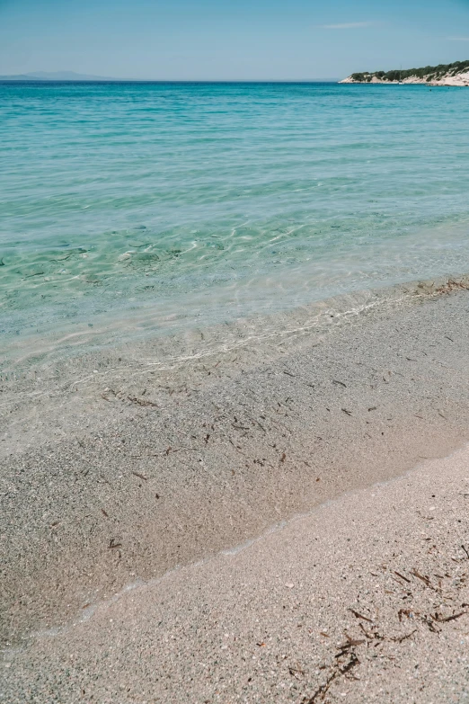 a couple of umbrellas sitting on top of a sandy beach, crystal clear water, coral-like pebbles, naples, julia sarda