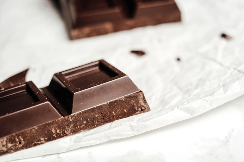 a piece of chocolate sitting on top of a piece of paper, trending on pexels, private press, background image, edible, magnesium, side profile shot