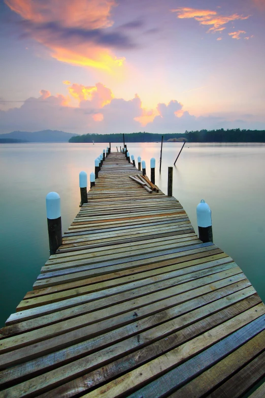 a dock in the middle of a body of water, walking down, pathway, sunset lighting, soothing colors