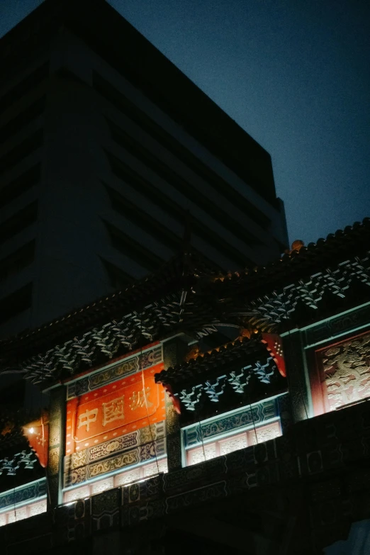 a tall building is lit up at night, a silk screen, by Shang Xi, unsplash, old town, low quality photo, faded, temple