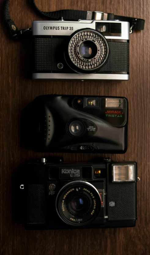 a couple of cameras sitting on top of a wooden table, by Adam Rex, high angle close up shot, medium-format print, black, 80s photo