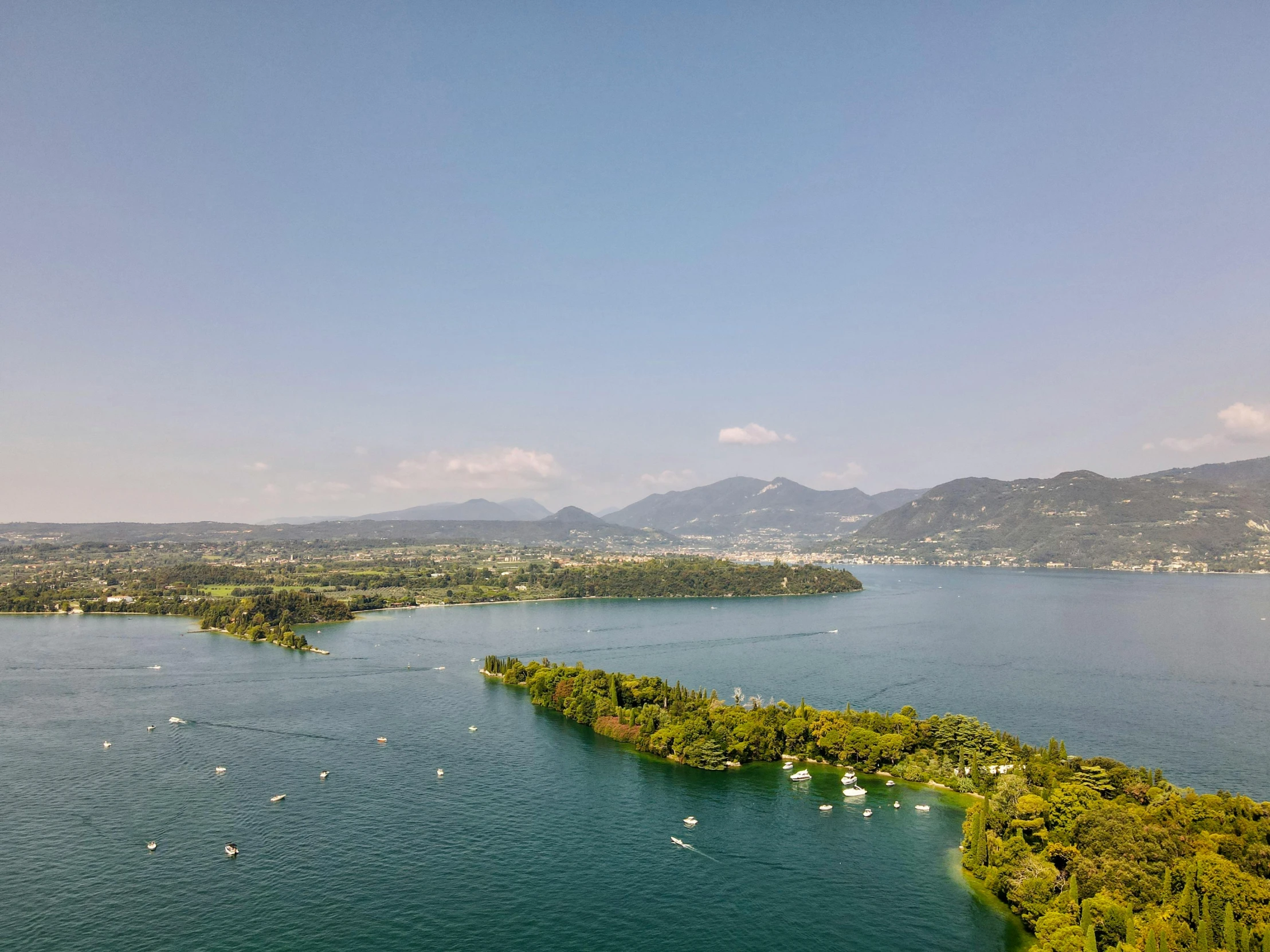 a large body of water surrounded by trees, pexels contest winner, photo of zurich, scattered islands, mountains and lakes, drone footage