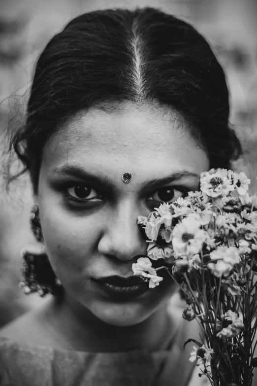 a woman holding a bunch of flowers in front of her face, a black and white photo, inspired by irakli nadar, pexels contest winner, assamese, piercing gaze, glaring at the camera, an film still