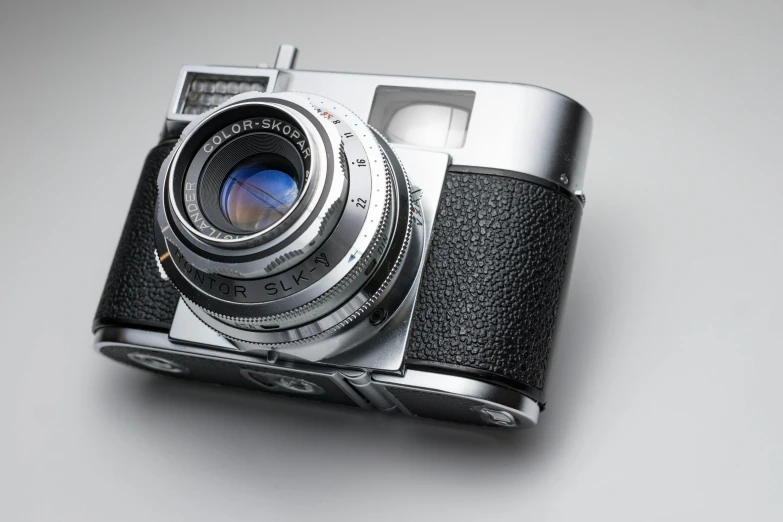 a close up of a camera on a table, by Sven Erixson, unsplash, photorealism, on a gray background, silver, medium format, restored color