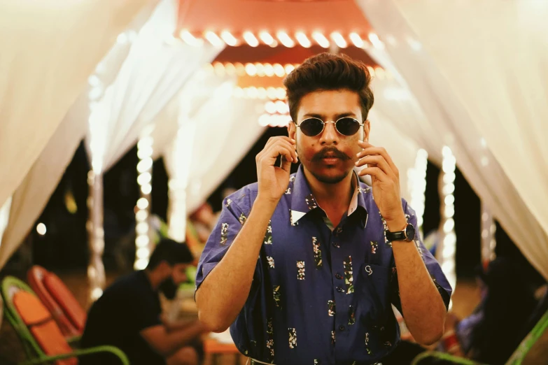 a man in a blue shirt talking on a cell phone, an album cover, trending on pexels, hindu aesthetic, sunglasses on, mid night, wearing festive clothing