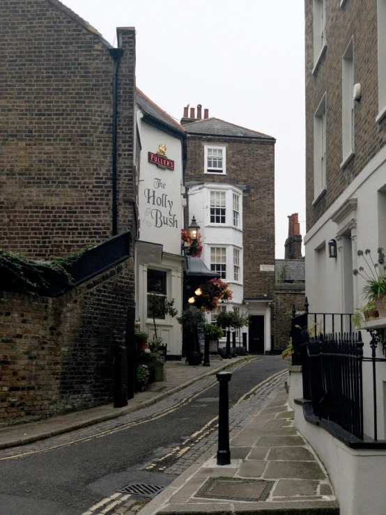 a narrow street lined with tall brick buildings, by Frank Mason, michelin starred restaurant, small path up to door, beer, grey sky